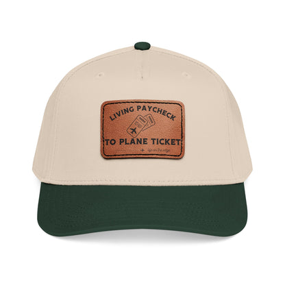 Beige and green cap with a brown leather patch displaying ''Living Paycheck to Plane Ticket"