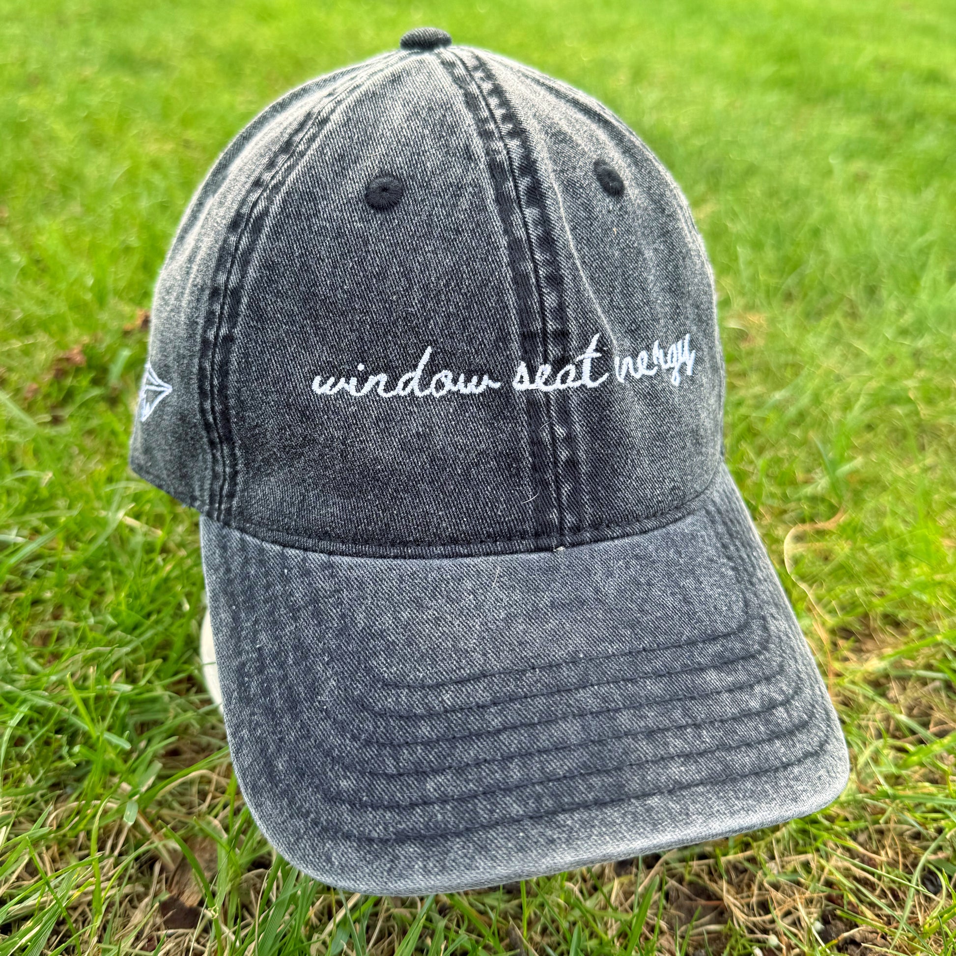 vintage black travel cap with 'window seat only' text on grass
